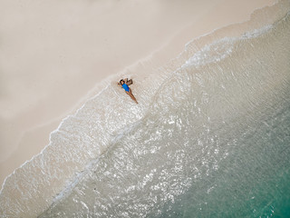 Ocean waves stroke the attractive body of a young girl in a swimming suit. Holidays concept.