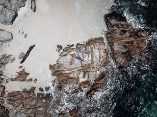 Drone photo of a rocky and sandy island in Thailand with a pretty chicky young girl.