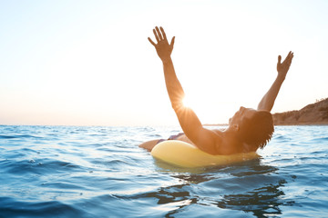 Young man with inflatable ring in sea