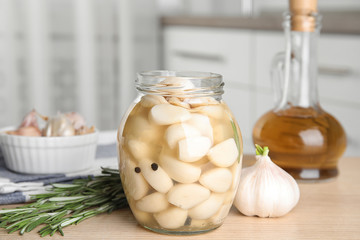 Composition with jar of pickled garlic on wooden table indoors