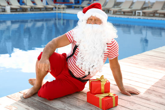 Authentic Santa Claus with gift boxes near pool at resort