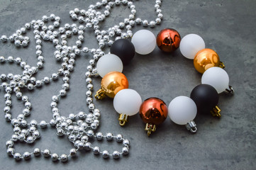 A wreath of Christmas balls with silver beads on a concrete surface. Christmas decoration for the interior.