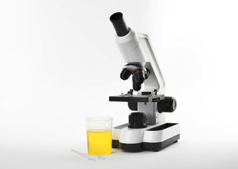 Laboratory ware with urine sample for analysis and microscope on white background