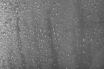 Glass with rain drops against light background