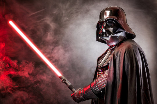 SAN BENEDETTO DEL TRONTO, ITALY. MAY 16, 2015. Portrait of Darth Vader costume replica with his sword . Lord Fener is a fictional character of Star Wars saga. Red grazing light and smoke
