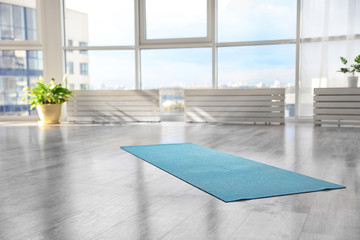 Unrolled light blue yoga mat on floor in room