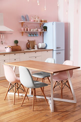 Stylish pink kitchen interior with dining table and chairs