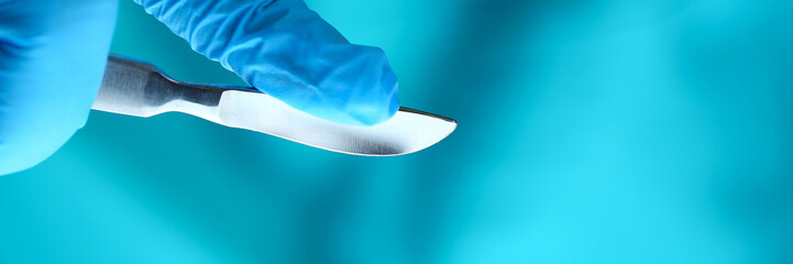 Surgeon arms in sterile uniform holding sharp knife