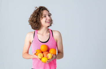 Young fitness woman with fruits oranges, grapefruit, peach, lemon.