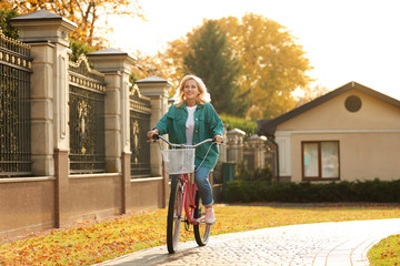 Fototapeta premium Mature woman riding bicycle outdoors. Active lifestyle