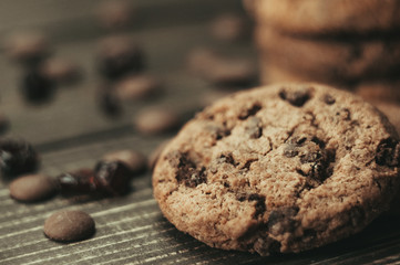 A stack of oatmeal cookies with chocolate pieces and candied fruits lies on a wooden table. Rustic table. Vintage toning. Dietary useful cookies without gluten. Copy space.