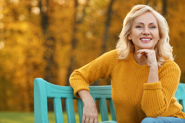 Portrait of happy mature woman on bench in park