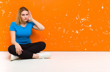 young blonde woman looking serious and curious, listening, trying to hear a secret conversation or...