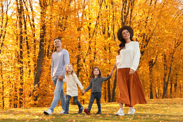 Happy family with little daughters walking in autumn park