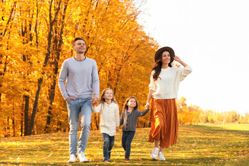 Happy family with little daughters walking in autumn park
