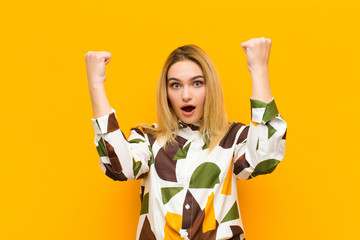 young blonde pretty woman celebrating an unbelievable success like a winner, looking excited and...