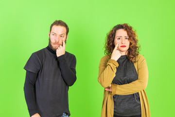 Young beautiful couple over green isolated background looking through hands with happy face. Looking at horizon.