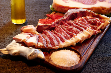 Fresh beef steake on a wood tray with salt.