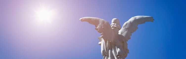 Rear view of antique statue angel in sunlight as a symbol of strength, truth and faith.