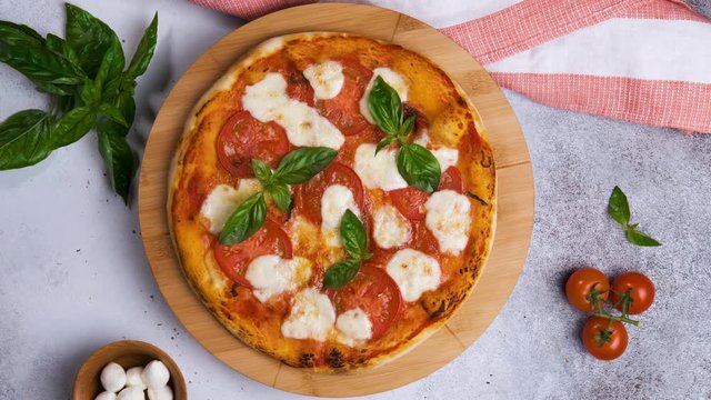 Tasty pizza Margherita with mozzarella cheese and tomatoes and ingredients on grey background. Top view, rotation 360