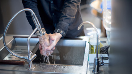 Washing hand in kitchen sink with modern stainless faucet. Saving water concept