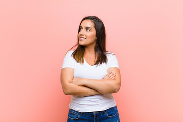 young pretty hispanic woman feeling happy, proud and hopeful, wondering or thinking, looking up to...