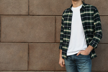Men in white t-shirt and checkered shirt against building, copy space
