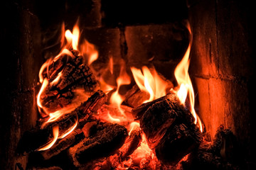 bright flame of fire burns in a fireplace in the old house in winter evening.Wood burning in a cozy fireplace at home.Fire to keep warm.fire flames with sparks on a black background