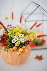 Bright autumn bouquet with flowers, berries and small apples in a pumpkin