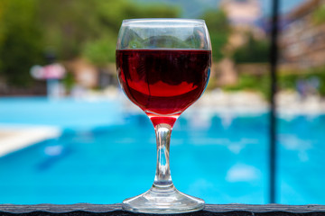 glass of red wine on the background of the pool