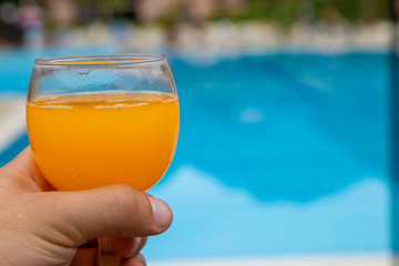 glass of orange juice on the background of the pool
