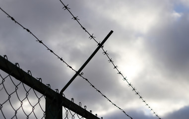 Barbed wire on fence, cloudy sky