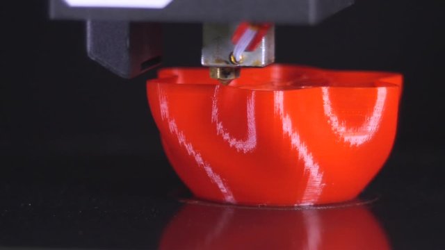 3D printer printing a red vase, Black background