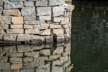Stonework of a bridge pylon with reflection in the water.