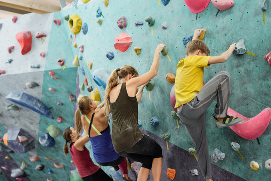 Young sportswomen and schoolboy in activewear creeping upon climbing wall - Powered by Adobe