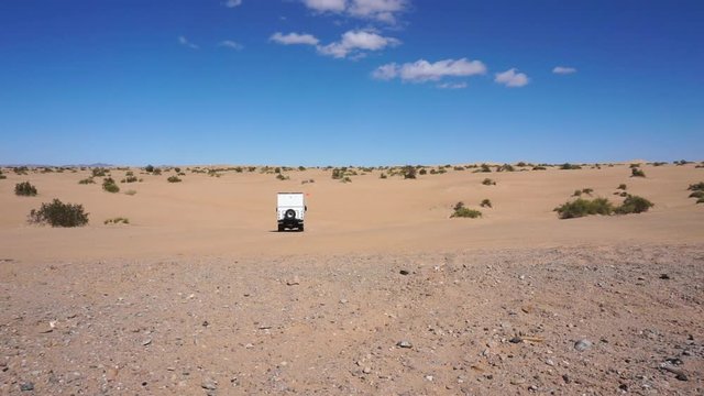 RV truck driving away in sandy desert in California, static slow motion