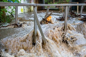 A powerful stream of water through the tunnel after a heavy rain, the water blows the footbridge