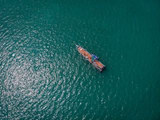 Naklejka premium Drone view of the big old blue motorboat with huge empty deck in blue sea, violet lifeboat at its side; vessels concept.