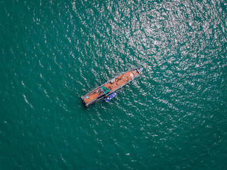 Drone view of the big old blue motorboat with huge empty deck in blue sea, violet lifeboat at its side; vessels concept.