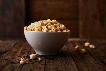 Delicious popcorn with caramel on wooden background..