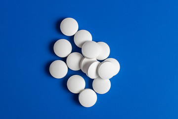 white round pills scattered blue background, chaotically scattered.