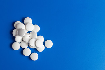 white round pills scattered blue background, chaotically scattered.