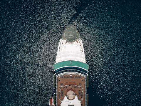 Aerial view of the deck, snout of the cruise liner with helideck and deck-chairs, blue sunny sea around. Liner equipment concept.