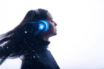 Portrait of beautiful woman with flowing hair in headphones listening music with closed eyes....