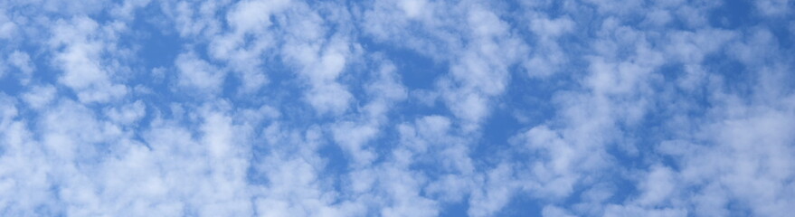 Weiße Schäfchenwolken vor blauen Himmel
