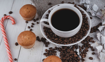 Cup of coffee with coffee beans and a croissant on vintage wooden table. Homemade croissant served with black coffee or americano. Coffee break with delicious croissant. Autumn composition still life.