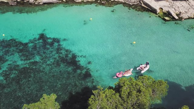 aerial view of people with floaties and a dinghi dragging them in the bay of Cala Pi, Mallorca 