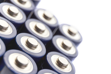 Batteries in rows. Close-up or macro of the positive poles of blue alkaline AA batteries. Image with selective focus isolated on top for copy space.	
