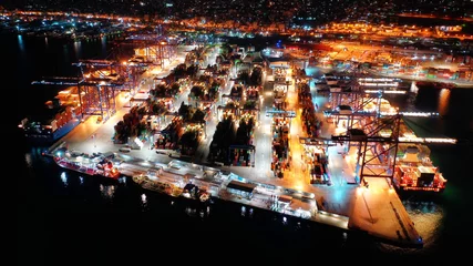 Poster Aerial night shot of illuminated industrial cargo truck size container terminal in Perama and Drapetsona commercial port near Piraeus, Attica, Greece © aerial-drone