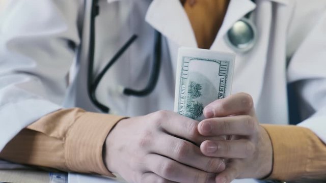 Doctor puts dollars in his pocket, close-up